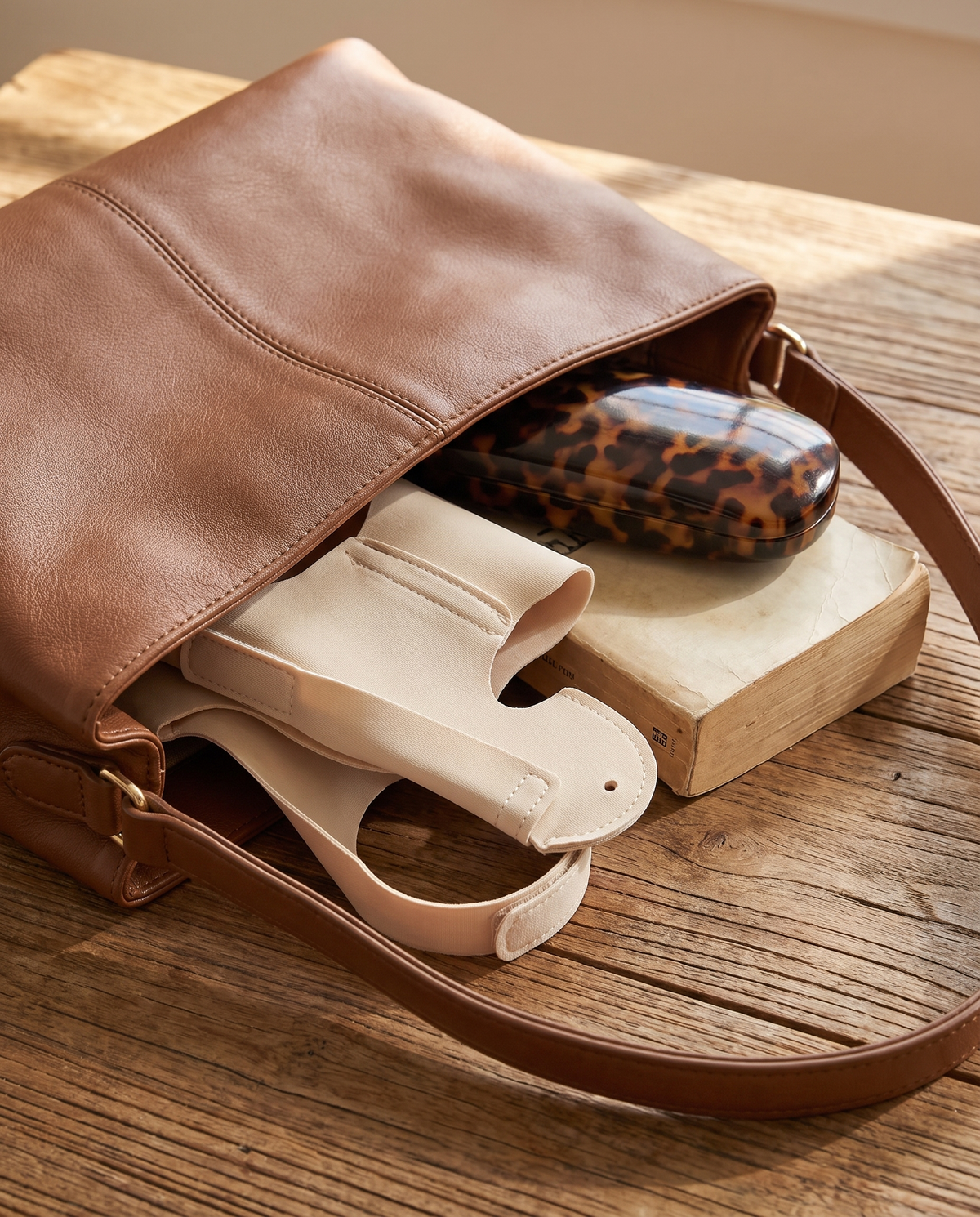 TrueToe folded into a handbag beside a glasses case and a paperback